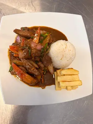 a plate of food with meat and vegetables and rice at Waranway Lodge Huayopata in Quillabamba