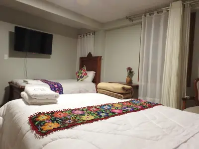 a bedroom with two beds and a flat screen tv at Rumi Wasi Inn Ollantaytambo in Ollantaytambo