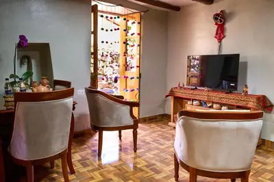 a room with two chairs and a table and a television at Rumi Wasi Inn Ollantaytambo in Ollantaytambo