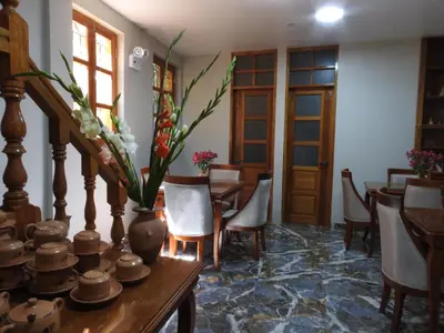 a dining room with tables and chairs and a vase with flowers at Rumi Wasi Inn Ollantaytambo in Ollantaytambo