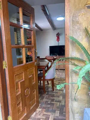 a living room with a wooden door and a table at Rumi Wasi Inn Ollantaytambo in Ollantaytambo
