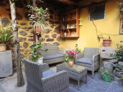 a patio with wicker chairs and tables and plants at Rumi Wasi Inn Ollantaytambo in Ollantaytambo