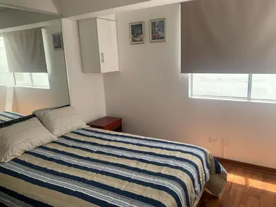 a bedroom with a bed with a striped blanket at Departamento en Miraflores in Lima