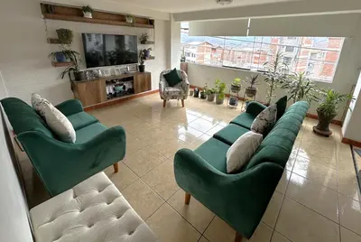 a living room with green couches and a tv at Adela's Home in Cusco