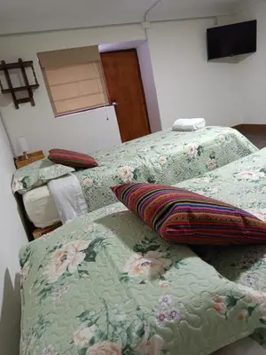 two beds with pillows on them in a bedroom at Hospedaje CASABLANCA URUBAMBA in Urubamba
