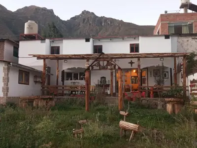 a white house with a pergola in a field at Hospedaje CASABLANCA URUBAMBA in Urubamba