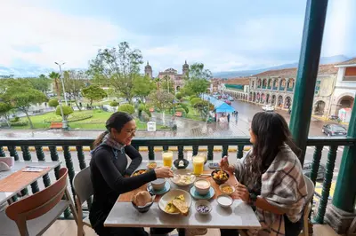 two women sitting at a table eating food on a balcony at Casa Andina Standard Ayacucho in Ayacucho