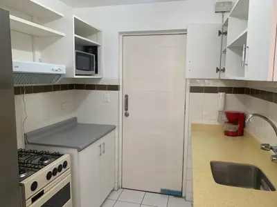a small kitchen with white cabinets and a sink at Departamento en Miraflores in Lima