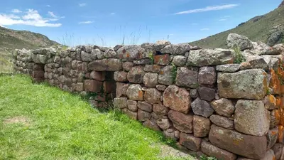 a stone wall in the middle of a field at Casa Qantu Huaytará in Huaytará