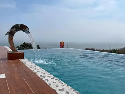 a swimming pool with a water fountain in front of the ocean at Dolphin house 915 in Punta Negra