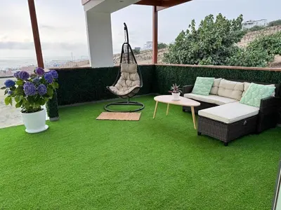 a green carpeted patio with a couch and a table at Dolphin house 915 in Punta Negra