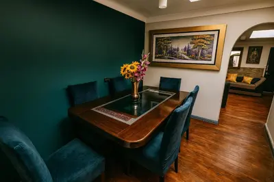 a dining room with a table with chairs and a vase with flowers at Panay Golden in Cusco