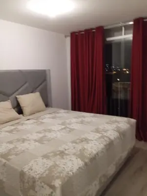 a bedroom with a bed with red curtains and a window at Se alquila habitación con cama King y baño privado in Lima