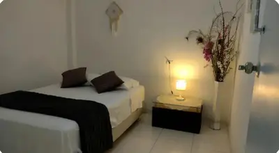 a bedroom with two beds and a lamp on a table at Apart Hotel Nazarenas in Ayacucho