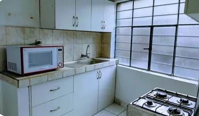 a small kitchen with a microwave and a sink at Apart Hotel Nazarenas in Ayacucho