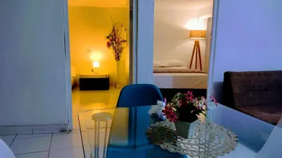 a room with a table with flowers and a lamp at Apart Hotel Nazarenas in Ayacucho