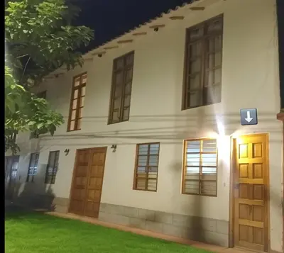 a white building with wooden doors and a green lawn at Loft Casa Yucay in Yucay