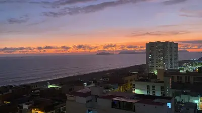 a view of the ocean at sunset from a city at Departamento in Magdalena del Mar in Lima