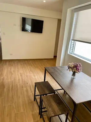 a living room with a table and a vase of flowers at Departamento in Magdalena del Mar in Lima
