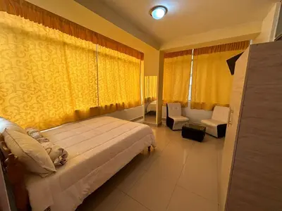 a bedroom with a bed and a couch and a window at Hotel Paraiso L & M in Huánuco