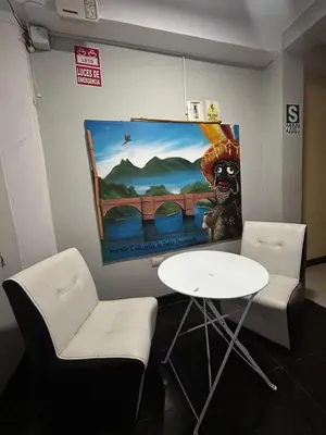a room with a table and two chairs and a painting at Hotel Paraiso L & M in Huánuco