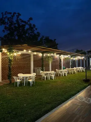 a group of tables and chairs in a yard at night at Oliver's Garden Country Hotel in Chincha