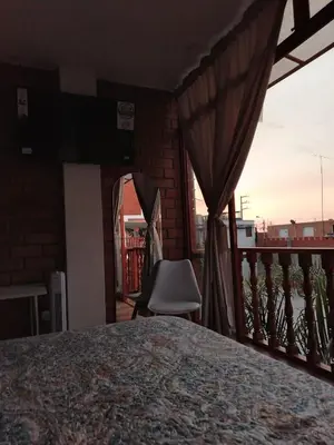 a room with a balcony with a chair and a window at Oliver's Garden Country Hotel in Chincha