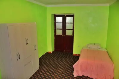 a green room with a bed and a door at Casita San Pedro in Cusco
