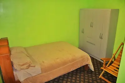 a green bedroom with a bed and a chair at Casita San Pedro in Cusco