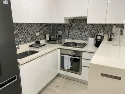 a kitchen with white cabinets and a stove and a sink at Monumental BR1 in Lima
