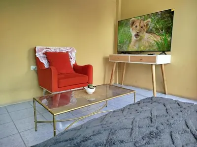 a living room with a red chair and a tv at Apart Hotel Valdelomar in Ayacucho