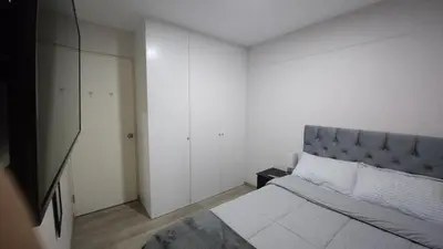 a white bedroom with a bed and a cabinet at Departamento con Increíble ubicación en San Miguel in Lima