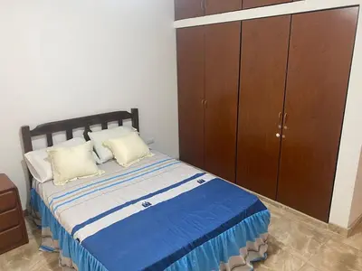 a bedroom with a bed and a wooden cabinet at Departamento cerca a Cerro Azul in Hualcará