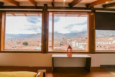 a room with two windows and a table with a lamp at QOSQO BELVEDERE, apartamento en Cuesta San Blas in Cusco