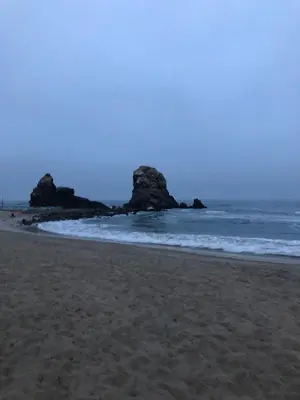 a sandy beach with rocks in the ocean at Lindo departamento muy cerca a la playa in Punta Negra