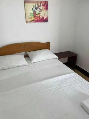a white bed with a wooden headboard and a table at Lindo departamento muy cerca a la playa in Punta Negra