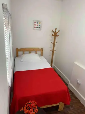 a bedroom with a bed with a red blanket and a cross at Mini Dpto frente al mar playa Pta N in Punta Negra