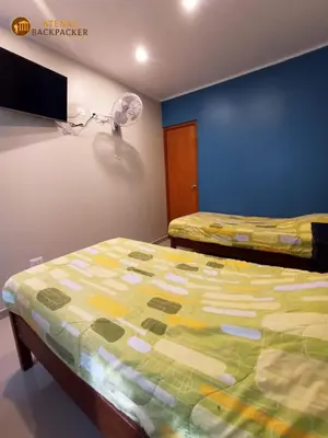 a bedroom with two beds and a fan at Atenas Backpacker Hospedaje in Paracas