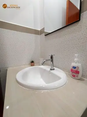 a white sink in a bathroom with a bottle of soap at Atenas Backpacker Hospedaje in Paracas