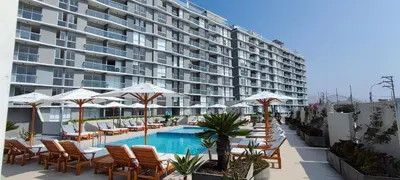 a hotel with a swimming pool and chairs and umbrellas at Apartamento San Bartolo in San Bartolo