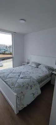a bed in a white room with a large window at Apartamento San Bartolo in San Bartolo