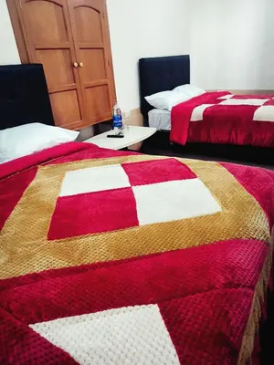 two beds in a room with a red and white quilt at Departamento 2 Waynapata Centro Historico Cusco in Cusco