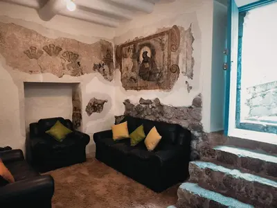 a living room with two black leather chairs and a painting at Departamento 2 Waynapata Centro Historico Cusco in Cusco