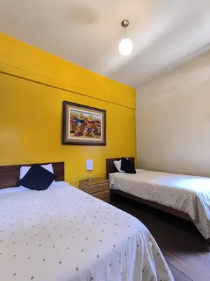 two beds in a room with yellow walls at Flying Dog Hostel in Lima
