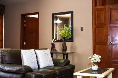 a living room with a leather couch and a mirror at Apart-Hotel El Cañaveral in Chincha