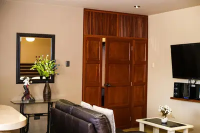a living room with a leather couch and a wooden door at Apart-Hotel El Cañaveral in Chincha