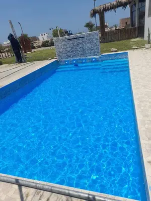 a blue swimming pool with a chair in a yard at Chinchacampoymar Casa de playa en Chincha in Chincha Baja