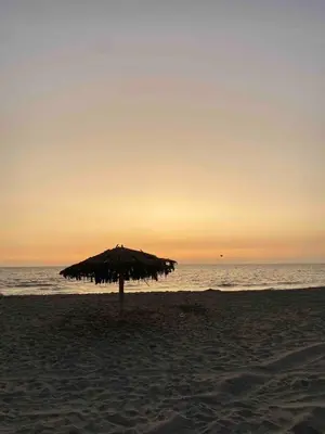 a straw umbrella on the beach at sunset at Chinchacampoymar Casa de playa en Chincha in Chincha Baja