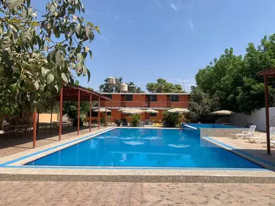 a large swimming pool with a building in the background at Hotel Los Pecanos in Ica