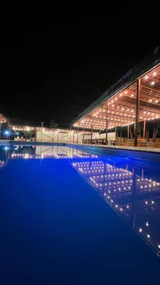 a swimming pool lit up at night with lights at Hotel Los Pecanos in Ica